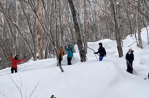 米子不動滝のスノーシューハイキングツアーで雪が覆う林間を歩く