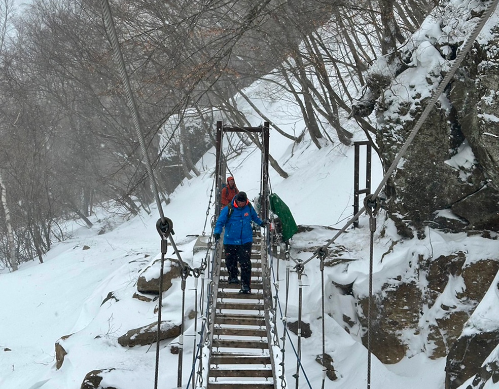 スノーシューハイキングコースの途中にある吊り橋を渡る参加者