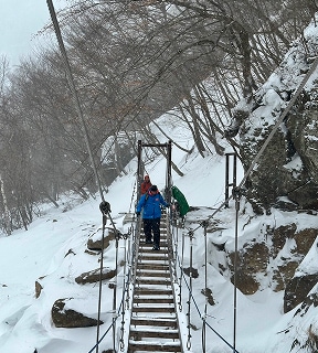 スノーシューハイキングコースの途中にある吊り橋を渡る参加者