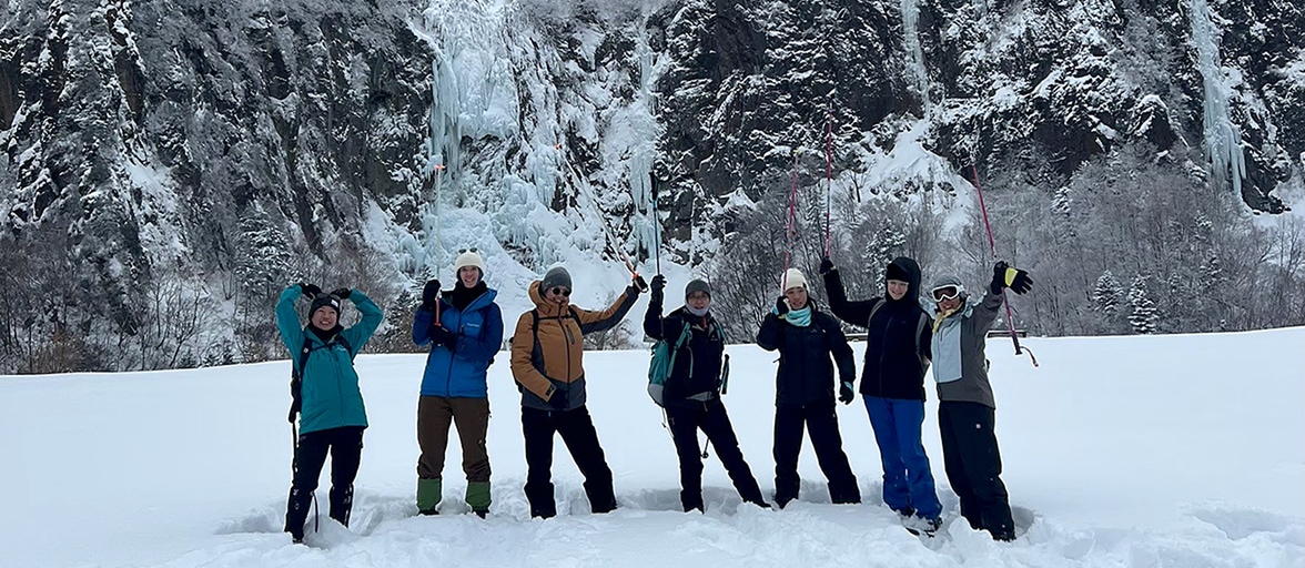 かつての鉱山跡の見晴台で不動滝をバックに記念撮影するスノーシューハイキングツアーの参加者