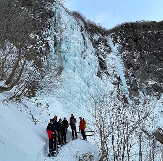 不動滝のすぐそばで記念撮影するスノーシューハイキングツアーの参加者