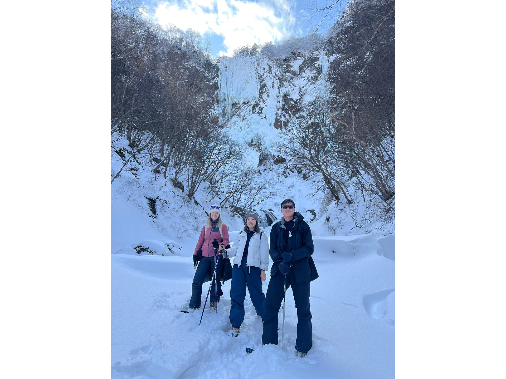 不動滝をバックに記念撮影するスノーシューハイキングツアーの参加者