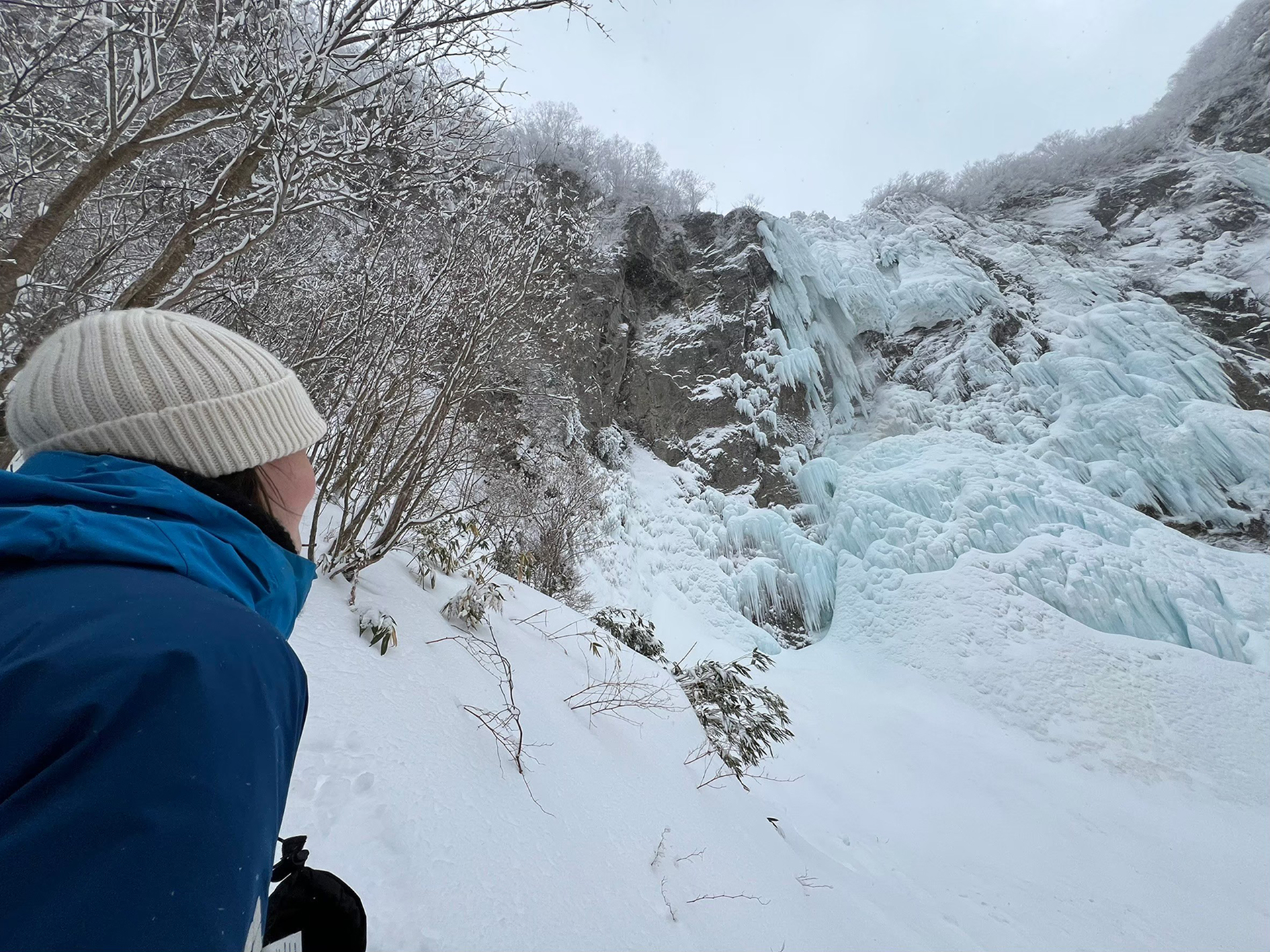 すぐそばで不動滝を見上げるスノーシューハイキングツアーの参加者